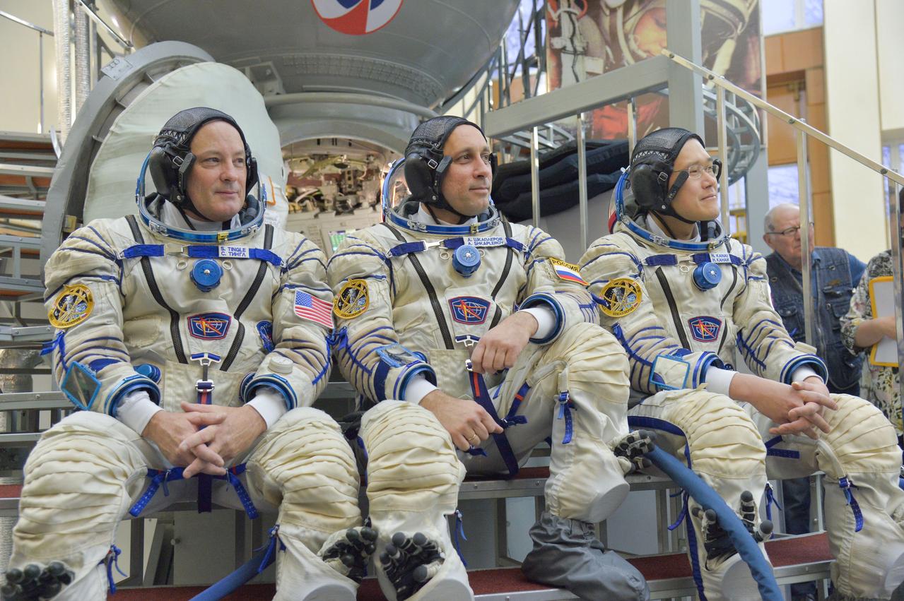 jsc2017e135205 - At the Gagarin Cosmonaut Training Center in Star City, Russia, Expedition 54-55 prime crewmembers Scott Tingle of NASA (left) Anton Shkaplerov of the Russian Federal Space Agency (Roscosmos, center) and Norishige Kanai of the Japan Aerospace Exploration Agency (JAXA, right) answer reporters’ questions Nov. 29 in front of a Soyuz spacecraft simulator as part of their final crew qualification exam activities. They will launch Dec. 17 on the Soyuz MS-07 spacecraft from the Baikonur Cosmodrome in Kazakhstan for a five-month mission on the International Space Station...NASA/Elizabeth Weissinger.