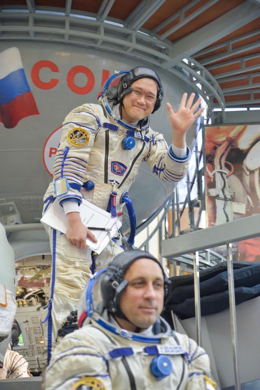 jsc2017e135210 - At the Gagarin Cosmonaut Training Center in Star City, Russia, Expedition 54-55 prime crewmember Norishige Kanai of the Japan Aerospace Exploration Agency (JAXA) waves to reporters as he boards a Soyuz spacecraft simulator Nov. 29 as part of the crew’s final qualification exam activities. Anton Shkaplerov of the Russian Federal Space Agency (Roscosmos) is seen in the foreground. They will launch along with Scott Tingle of NASA Dec. 17 on the Soyuz MS-07 spacecraft from the Baikonur Cosmodrome in Kazakhstan for a five-month mission on the International Space Station...NASA/Elizabeth Weissinger.