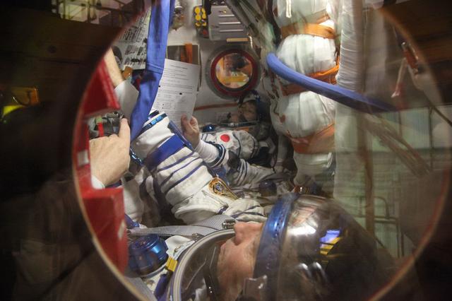 jsc2017e136450 - In the Integration Facility at the Baikonur Cosmodrome in Kazakhstan, Expedition 54-55 crewmembers Norishige Kanai of the Japan Aerospace Exploration Agency (JAXA, top) and Scott Tingle of NASA (bottom) run through their procedures in the Soyuz MS-07 spacecraft Dec. 5 as part of the first fit check dress rehearsal activities. Kanai, Tingle and Anton Shkaplerov of the Russian Federal Space Agency (Roscosmos) will launch Dec. 17 in the Soyuz MS-07 vehicle for a five-month mission on the International Space Station...Courtesy of Roscosmos.