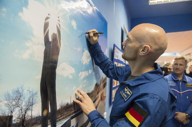 NASA image: jsc2017e136941 - At the Baikonur Museum in Baikonur, Kazakhstan, Expedition 54-55 backup crewmember Alexander Gerst of the European Space Agency signs a picture of the statue of Yuri Gagarin, the first human to fly in space Dec. 6 as his backup crewmate, S