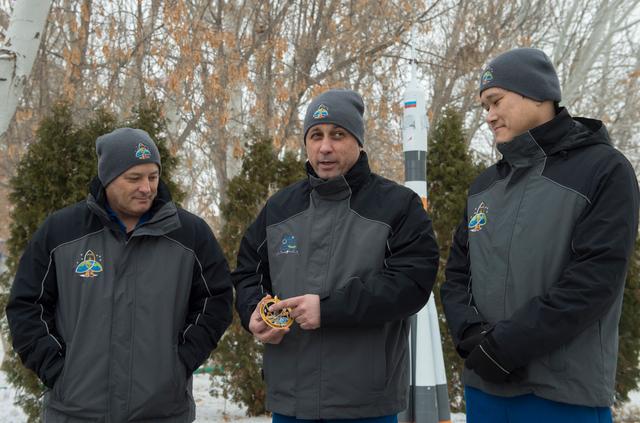 jsc2017e137333 - At their Cosmonaut Hotel crew quarters in Baikonur, Kazakhstan, Expedition 54-55 prime crewmembers Scott Tingle of NASA (left), Anton Shkaplerov of the Russian Federal Space Agency (Roscosmos, center) and Norishige Kanai of the Japan Aerospace Exploration Agency (JAXA, right) discuss the significance of their Soyuz mission insignia during a question and answer session with reporters Dec. 11. They will launch Dec. 17 on the Soyuz MS-07 spacecraft from the Baikonur Cosmodrome for a five month mission on the International Space Station...Andrey Shelepin / Gagarin Cosmonaut Training Center.