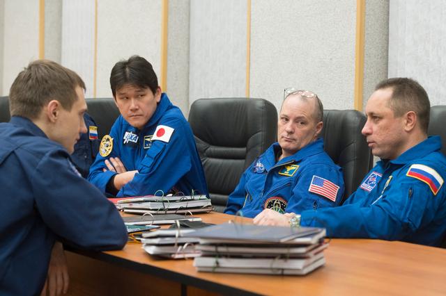 jsc2017e137335 - At their Cosmonaut Hotel crew quarters in Baikonur, Kazakhstan, Expedition 54-55 prime crewmembers Norishige Kanai of the Japan Aerospace Exploration Agency (JAXA, left), Scott Tingle of NASA (center) and Anton Shkaplerov of the Russian Federal Space Agency (Roscosmos, right) confer with Soyuz spacecraft trainers Dec. 11 as part of their pre-launch training. They will launch Dec. 17 on the Soyuz MS-07 spacecraft from the Baikonur Cosmodrome for a five month mission on the International Space Station...Andrey Shelepin / Gagarin Cosmonaut Training Center.