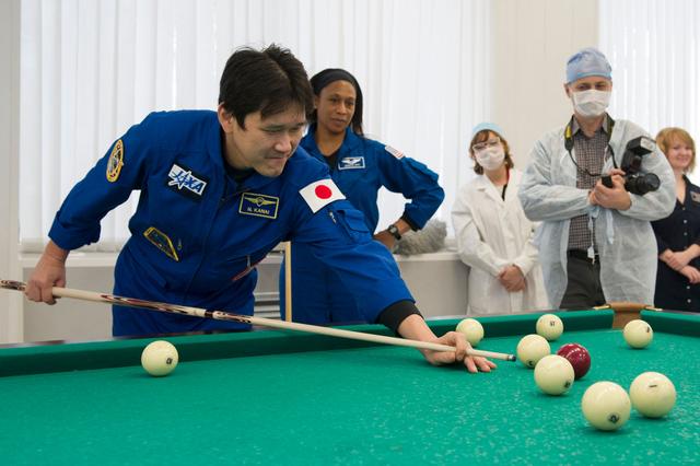 jsc2017e137338 - At the Cosmonaut Hotel crew quarters in Baikonur, Kazakhstan, Expedition 54-55 prime crewmember Norishige Kanai of the Japan Aerospace Exploration Agency (JAXA) tries his hand at a game of billiards Dec. 11 during a break in pre-launch training while backup crewmember Jeanette Epps of NASA looks on. Kanai, Scott Tingle of NASA and Anton Shkaplerov of the Russian Federal Space Agency (Roscosmos) will launch Dec. 17 on the Soyuz MS-07 spacecraft from the Baikonur Cosmodrome for a five month mission on the International Space Station...Andrey Shelepin / Gagarin Cosmonaut Training Center.