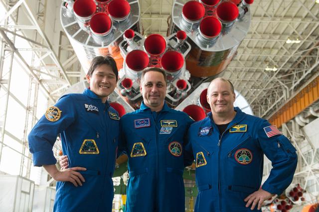 jsc2017e138118 - In the Integration Facility at the Baikonur Cosmodrome in Kazakhstan, the Expedition 54-55 prime crewmembers pose for pictures Dec. 13 in front of the first stage of the Soyuz booster rocket. From left to right are Norishige Kanai of the Japan Aerospace Exploration Agency (JAXA), Scott Tingle of NASA and Anton Shkaplerov of the Russian Federal Space Agency (Roscosmos), who will launch Dec. 17 on the Soyuz MS-07 spacecraft for a five month mission on the International Space Station...Andrey Shelepin/Gagarin Cosmonaut Training Center.