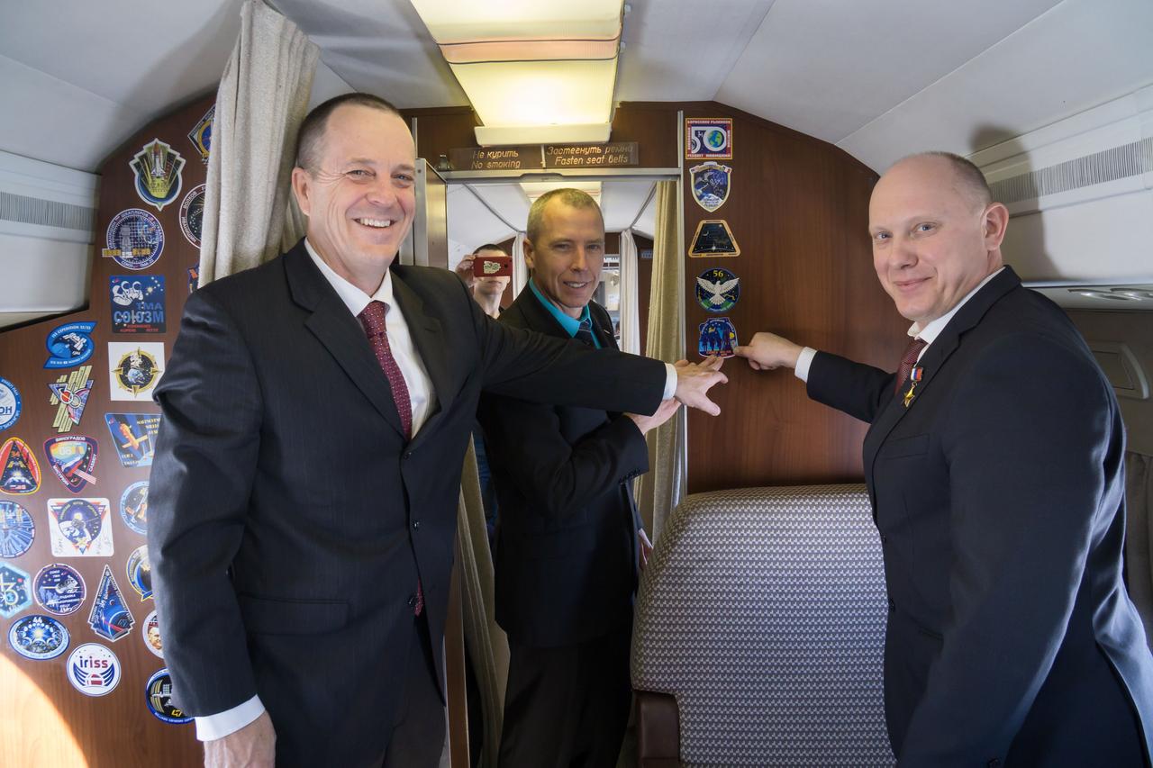 jsc2018e010814 - Aboard a Gagarin Cosmonaut Training Center aircraft en route to their launch site at the Baikonur Cosmodrome in Kazakhstan, Expedition 55 crewmembers Ricky Arnold of NASA (left), Drew Feustel of NASA (center) and Oleg Artemyev of Roscosmos (right) point to their Soyuz crew patch March 4 during their flight from their training base outside of Moscow. The trio will launch March 21 on the Soyuz MS-08 spacecraft for a five month mission on the International Space Station...NASA/Victor Zelentsov.