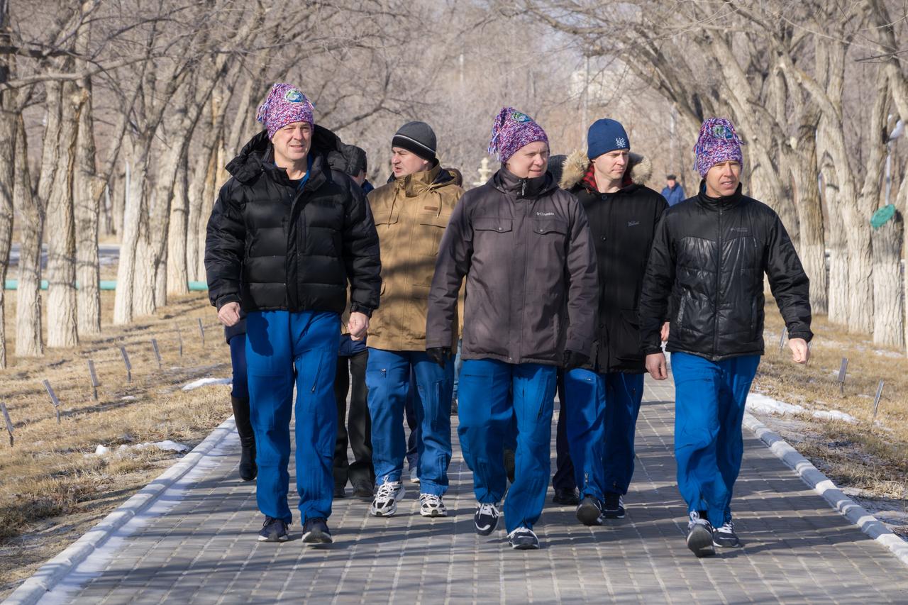 jsc2018e025539 - At the Cosmonaut Hotel crew quarters in Baikonur, Kazakhstan, Expedition 55 crewmembers Ricky Arnold of NASA (left), Oleg Artemyev of Roscosmos (center) and Drew Feustel of NASA (right) take a stroll down the Walk of Cosmonauts March 15 as part of their pre-launch activities. They will launch March 21 on the Soyuz MS-08 spacecraft from the Baikonur Cosmodrome on a five-month mission to the International Space Station...NASA/Victor Zelentsov.