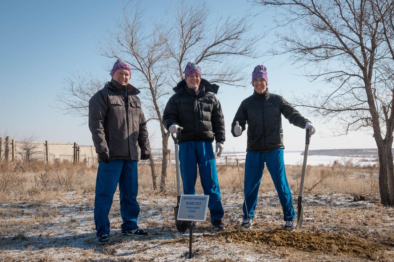 jsc2018e025541 - At the Cosmonaut Hotel crew quarters in Baikonur, Kazakhstan, Expedition 55 crewmembers Oleg Artemyev of Roscosmos (left), Ricky Arnold of NASA (center) and Drew Feustel of NASA (right) pose for pictures March 15 after Feustel planted a tree in his name in traditional pre-launch activities. They will launch March 21 on the Soyuz MS-08 spacecraft from the Baikonur Cosmodrome on a five-month mission to the International Space Station...NASA/Victor Zelentsov.