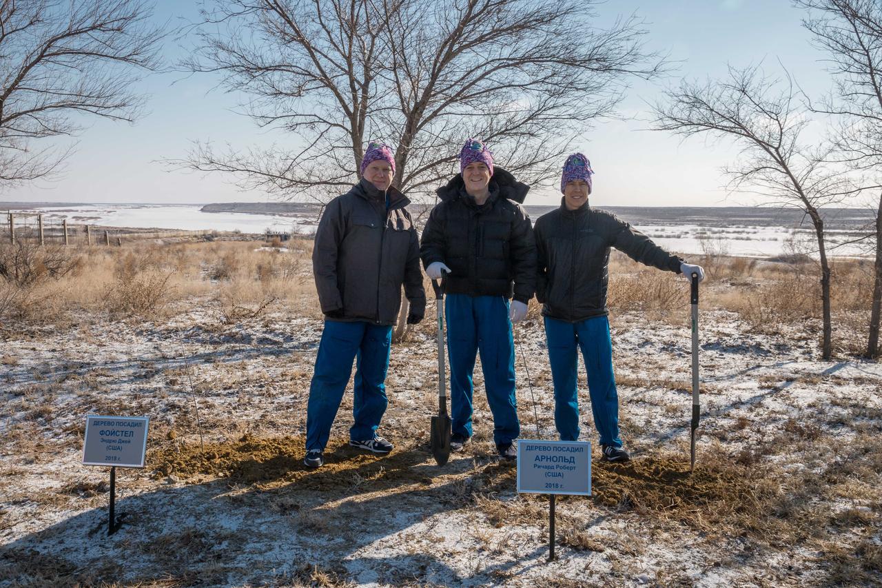jsc2018e025543 - At the Cosmonaut Hotel crew quarters in Baikonur, Kazakhstan, Expedition 55 crewmembers Oleg Artemyev of Roscosmos (left), Ricky Arnold of NASA (center) and Drew Feustel of NASA (right) pose for pictures March 15 after Arnold planted a tree in his name in traditional pre-launch activities. They will launch March 21 on the Soyuz MS-08 spacecraft from the Baikonur Cosmodrome on a five-month mission to the International Space Station...NASA/Victor Zelentsov.