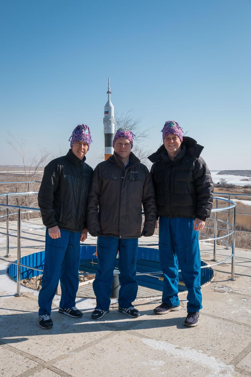 jsc2018e025546 - At the Cosmonaut Hotel crew quarters in Baikonur, Kazakhstan, Expedition 55 crewmembers Drew Feustel of NASA (left), Oleg Artemyev of Roscosmos (center) and Ricky Arnold of NASA (right) pose for pictures by a Soyuz model March 15 as part of their pre-launch activities. They will launch March 21 on the Soyuz MS-08 spacecraft from the Baikonur Cosmodrome on a five-month mission to the International Space Station...NASA/Victor Zelentsov.
