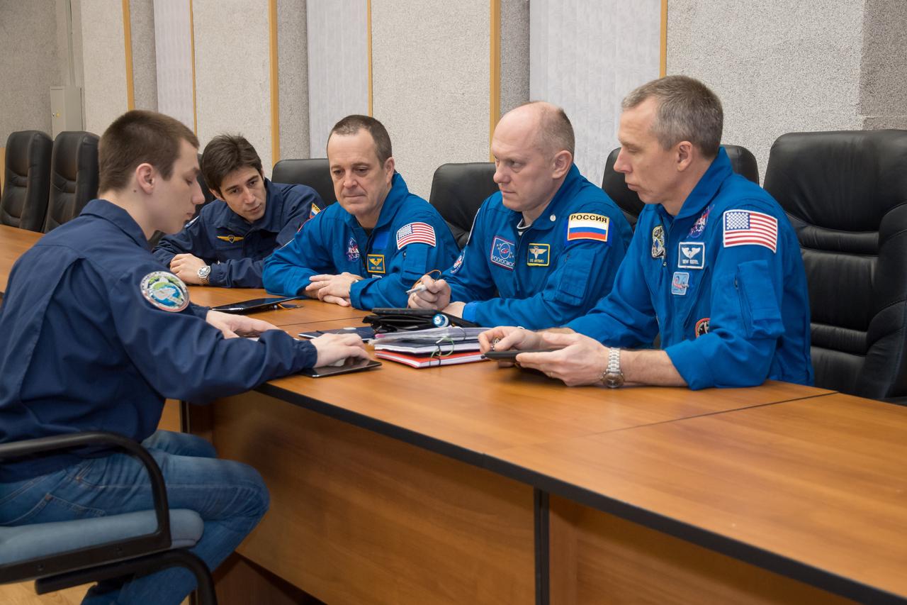 jsc2018e025550 - At the Cosmonaut Hotel crew quarters in Baikonur, Kazakhstan, Expedition 55 crewmembers Ricky Arnold of NASA (second from left), Oleg Artemyev of Roscosmos (second from right) and Drew Feustel of NASA (right) listen to training instructors March 15 as part of their pre-launch activities. They will launch March 21 on the Soyuz MS-08 spacecraft from the Baikonur Cosmodrome on a five-month mission to the International Space Station...NASA/Victor Zelentsov.