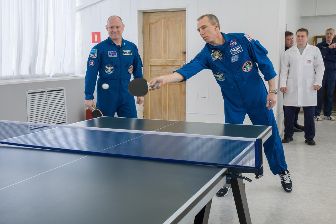 jsc2018e025555 - At the Cosmonaut Hotel crew quarters in Baikonur, Kazakhstan, Expedition 55 crewmember Drew Feustel of NASA (right) tries his hand at a game of ping-pong March 15 as his crewmate, Oleg Artemyev of Roscosmos (left) looks on. Along with Ricky Arnold of NASA, they will launch March 21 on the Soyuz MS-08 spacecraft from the Baikonur Cosmodrome on a five-month mission to the International Space Station...NASA/Victor Zelentsov.