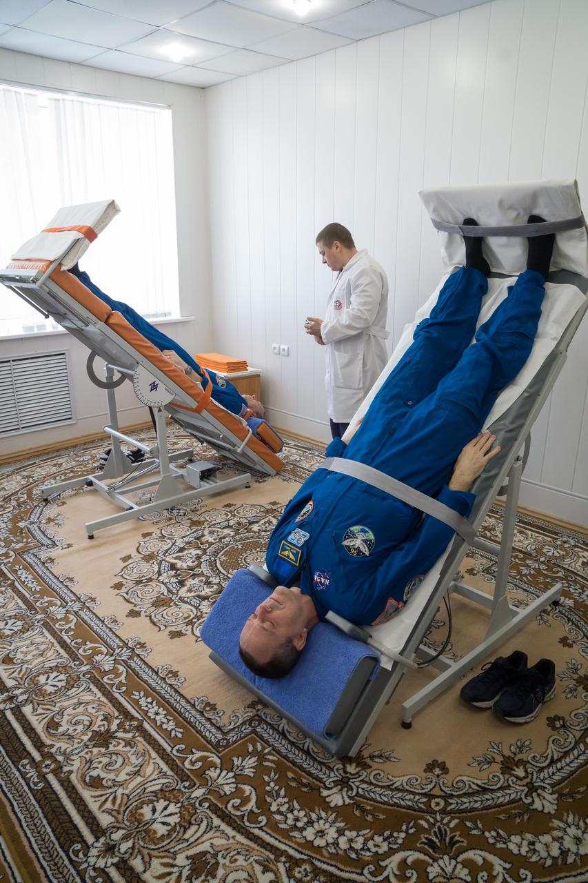 jsc2018e025556 - At the Cosmonaut Hotel crew quarters in Baikonur, Kazakhstan, Expedition 55 crewmembers Drew Feustel of NASA (top) and Ricky Arnold of NASA (bottom) conduct tests of their vestibular systems on tilt tables March 15 as part of pre-launch activities. Along with Oleg Artemyev of Roscosmos, they will launch March 21 on the Soyuz MS-08 spacecraft from the Baikonur Cosmodrome on a five-month mission to the International Space Station...NASA/Victor Zelentsov.
