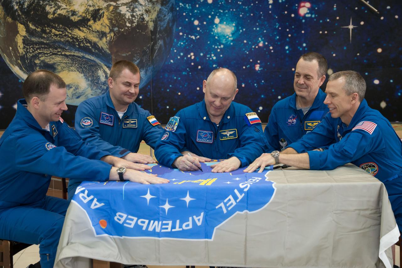 jsc2018e025593 - In the Korolev Museum at the Baikonur Cosmodrome in Kazakhstan, the Expedition 55 prime and backup crewmembers sign a flag bearing their Soyuz MS-08 crew patch insignia March 16 during a traditional preflight tour of the museum. From left to right are backup crewmembers Nick Hague of NASA and Alexey Ovchinin of Roscosmos and prime crewmembers Oleg Artemyev of Roscosmos, Ricky Arnold of NASA and Drew Feustel of NASA, who will launch March 21 on the Soyuz MS-08 spacecraft for a five-month mission on the International Space Station...NASA/Victor Zelentsov.