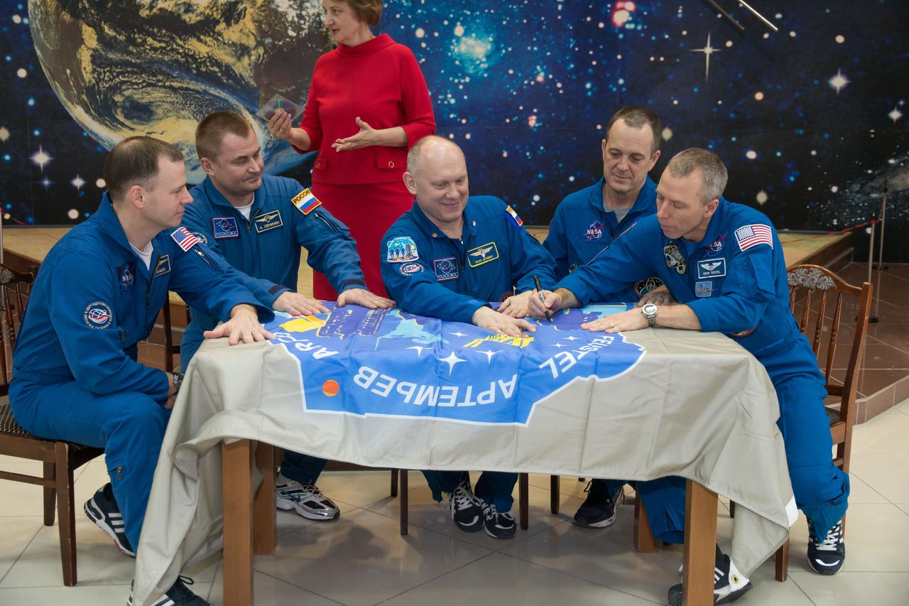 jsc2018e025594 - In the Korolev Museum at the Baikonur Cosmodrome in Kazakhstan, the Expedition 55 prime and backup crewmembers sign a flag bearing their Soyuz MS-08 crew patch insignia March 16 during a traditional preflight tour of the museum. From left to right are backup crewmembers Nick Hague of NASA and Alexey Ovchinin of Roscosmos and prime crewmembers Oleg Artemyev of Roscosmos, Ricky Arnold of NASA and Drew Feustel of NASA, who will launch March 21 on the Soyuz MS-08 spacecraft for a five-month mission on the International Space Station...NASA/Victor Zelentsov.