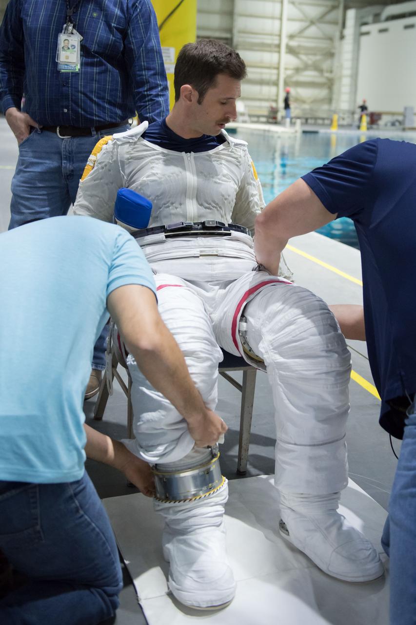 jsc2018e035757 (04-12-2018) --- 2017 Canadian Space Agency astronaut candidate Joshua Kutryk in a Liquid Cooling and Ventilation Garment and being helped into a spacesuit prior to underwater spacewalk training at NASA Johnson Space Center’s Neutral Buoyancy Laboratory. The cooling garment distributes water throughout to help keep him cool while training underwater in the spacesuit. Photo Credit: (NASA/David DeHoyos)