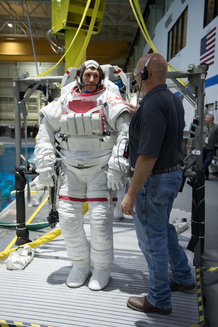 jsc2018e035780 (04-12-20180 --- Canadian Space Agency astronaut candidate Joshua Kutryk is being helped into a spacesuit prior to underwater spacewalk training at NASA Johnson Space Center’s Neutral Buoyancy Laboratory. Photo Credit: (NASA/David DeHoyos)
