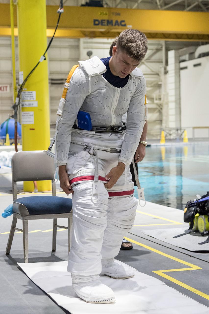 jsc2018e035900 (April 11, 2018) --- 2017 NASA astronaut candidate Matthew Dominick in a Liquid Cooling and Ventilation Garment helps himself into a spacesuit prior to underwater spacewalk training at NASA Johnson Space Center’s Neutral Buoyancy Laboratory. Photo Credit: (NASA/Josh Valcarcel)