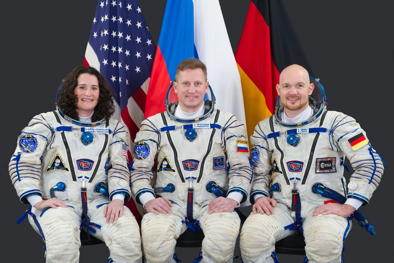 jsc2018e038854 (November 14, 2017) --- Expedition 56-57 crew members (from left) Serena Auñón-Chancellor of NASA, Sergey Prokopyev of Roscosmos and Alexander Gerst of ESA (European Space Agency) pose for a crew portrait in Sokol launch and entry suits at the Gagarin Cosmonaut Training Center in Star City, Russia.