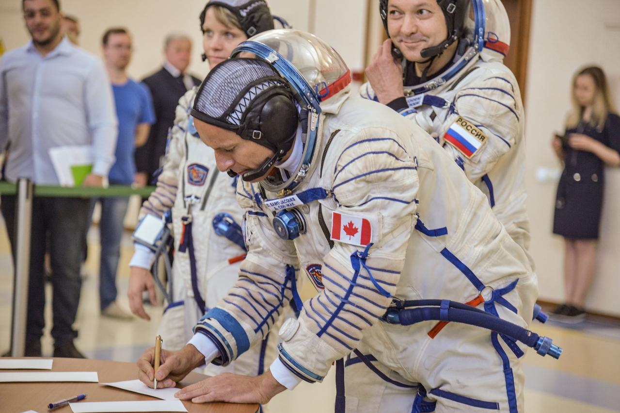 jsc2018e043405 (May 10, 2018) --- At the Gagarin Cosmonaut Training Center in Star City, Russia, Expedition 56 backup crew member David Saint-Jacques of the Canadian Space Agency signs in for his final Soyuz qualification exam May 10 as crewmates Anne McClain of NASA (left) and Oleg Kononenko of Roscosmos look on. They are the backups to the prime crew of Serena Aunon-Chancellor of NASA, Sergey Prokopyev of Roscosmos and Alexander Gerst of the European Space Agency, who will launch June 6 from the Baikonur Cosmodrome in Kazakhstan on the Soyuz MS-09 spacecraft for a six-month mission on the International Space Station...NASA/Elizabeth Weissinger.