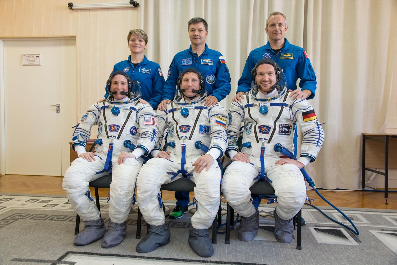 jsc2018e049996 - In the Integration Facility at the Baikonur Cosmodrome in Kazakhstan, the Expedition 56 prime and backup crewmembers pose for pictures May 20 during their first Soyuz fit check dress rehearsal activities. In the front row are prime crewmembers Serena Aunon-Chancellor of NASA (left), Sergey Prokopyev of Roscosmos (center) and Alexander Gerst of the European Space Agency (right). In the back row are their backups, Anne McClain of NASA (left), Oleg Kononenko of Roscosmos (center) and David Saint-Jacques of the Canadian Space Agency (right). Aunon-Chancellor, Prokopyev and Gerst will launch June 6 on the Soyuz MS-09 spacecraft from Baikonur for a six-month mission on the International Space Station...NASA/Victor Zelentsov.
