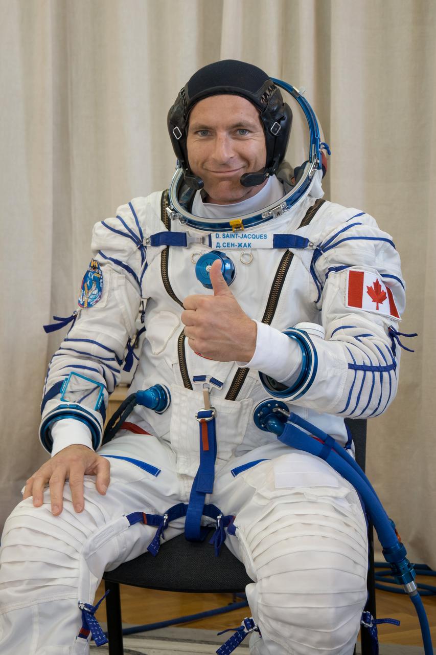 jsc2018e050008 - In the Integration Facility at the Baikonur Cosmodrome in Kazakhstan, Expedition 56 backup crewmember David Saint-Jacques of the Canadian Space Agency flashes a thumbs up for reporters May 20 during the first Soyuz fit check dress rehearsal activities. Saint-Jacques is one of the backup crewmembers to the prime crew, Serena Aunon-Chancellor of NASA, Sergey Prokopyev of Roscosmos and Alexander Gerst of the European Space Agency who will launch June 6 on the Soyuz MS-09 spacecraft from Baikonur for a six-month mission on the International Space Station...NASA/Victor Zelentsov.