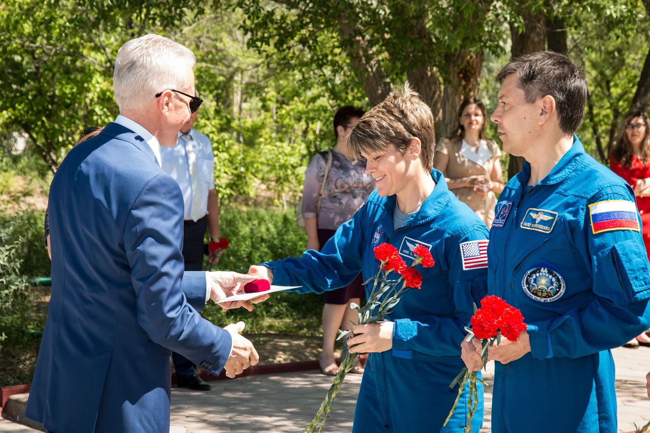 jsc2018e050015 - At the Cosmonaut Hotel crew quarters in Baikonur, Kazakhstan, Expedition 56 backup crewmember Anne McClain of NASA receives a silver pin bearing an emblem of the town from a local official as crewmate Oleg Kononenko of Roscosmos looks on. Along with David Saint-Jacques of the Canadian Space Agency, they are serving as backups to the prime crew, Serena Aunon-Chancellor of NASA, Sergey Prokopyev of Roscosmos and Alexander Gerst of the European Space Agency, who will launch June 6 on the Soyuz MS-09 spacecraft from Baikonur for a six-month mission on the International Space Station...NASA/Victor Zelentsov.