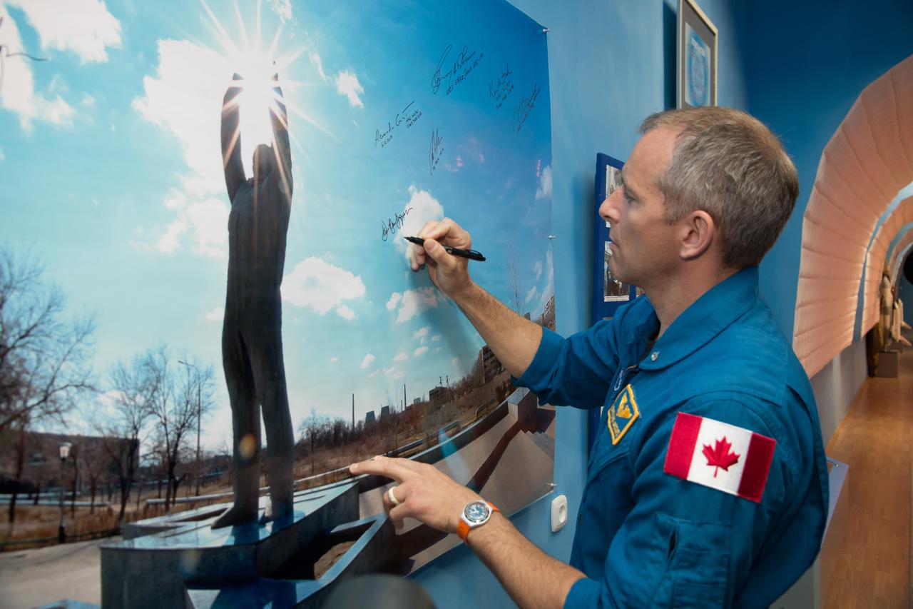 jsc2018e050022 - At the Baikonur Museum in Baikonur, Kazakhstan, Expedition 56 backup crewmember David Saint-Jacques of the Canadian Space Agency signs a wall photo May 21 depicting the statue of Yuri Gagarin, the first human to fly in space, during traditional pre-launch activities. Saint-Jacques is one of the backups to the prime crewmembers, Serena Aunon-Chancellor of NASA, Sergey Prokopyev of Roscosmos and Alexander Gerst of the European Space Agency, who will launch June 6 on the Soyuz MS-09 spacecraft from Baikonur for a six-month mission on the International Space Station...NASA/Victor Zelentsov.