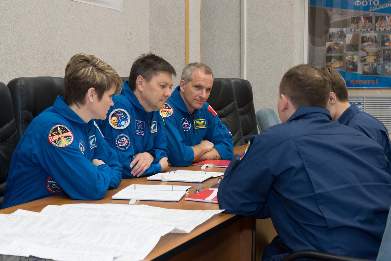 jsc2018e050819 - At the Cosmonaut Hotel crew quarters in Baikonur, Kazakhstan, Expedition 56 backup crewmembers Anne McClain of NASA (left), Oleg Kononenko of Roscosmos (center) and David Saint-Jacques of the Canadian Space Agency (right) review training documents with a Gagarin Cosmonaut Training Center instructor May 29 as they prepare for the upcoming launch of the prime crewmembers, Serena Aunon-Chancellor of NASA, Sergey Prokopyev of Roscosmos and Alexander Gerst of the European Space Agency, who will launch June 6 from the Baikonur Cosmodrome in Kazakhstan on the Soyuz MS-09 spacecraft for a six-month mission on the International Space Station...NASA/Victor Zelentsov.