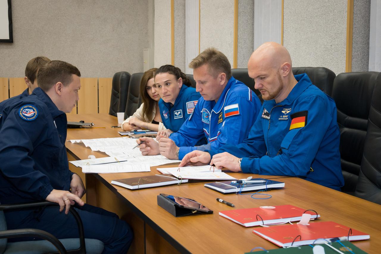 jsc2018e050823 - At the Cosmonaut Hotel crew quarters in Baikonur, Kazakhstan, Expedition 56 crewmembers Serena Aunon-Chancellor of NASA (left), Sergey Prokopyev of Roscosmos (center) and Alexander Gerst of the European Space Agency (right) review training documents with a Gagarin Cosmonaut Training Center instructor (far left) May 29 as they prepare for their upcoming launch. Aunon-Chancellor, Prokopyev and Gerst will launch June 6 from the Baikonur Cosmodrome in Kazakhstan on the Soyuz MS-09 spacecraft for a six-month mission on the International Space Station...NASA/Victor Zelentsov.