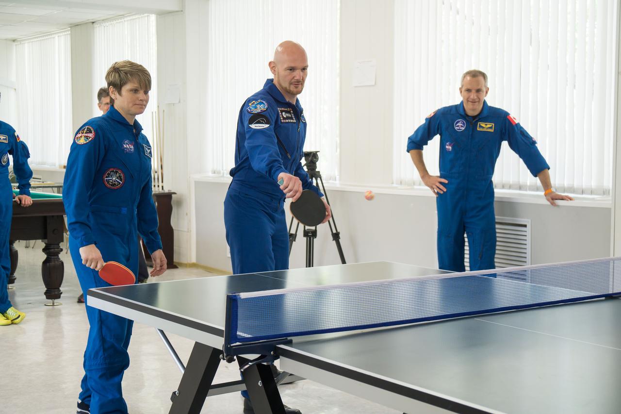 jsc2018e050827 - At the Cosmonaut Hotel crew quarters in Baikonur, Kazakhstan, Expedition 56 prime crewmember Alexander Gerst of the European Space Agency (center) tries his hand at game of ping-pong May 29 as backup crewmembers Anne McClain of NASA (left) and David Saint-Jacques of the Canadian Space Agency (right) look on. Gerst, Serena Aunon-Chancellor of NASA and Sergey Prokopyev of Roscosmos will launch June 6 from the Baikonur Cosmodrome in Kazakhstan on the Soyuz MS-09 spacecraft for a six-month mission on the International Space Station...NASA/Victor Zelentsov.