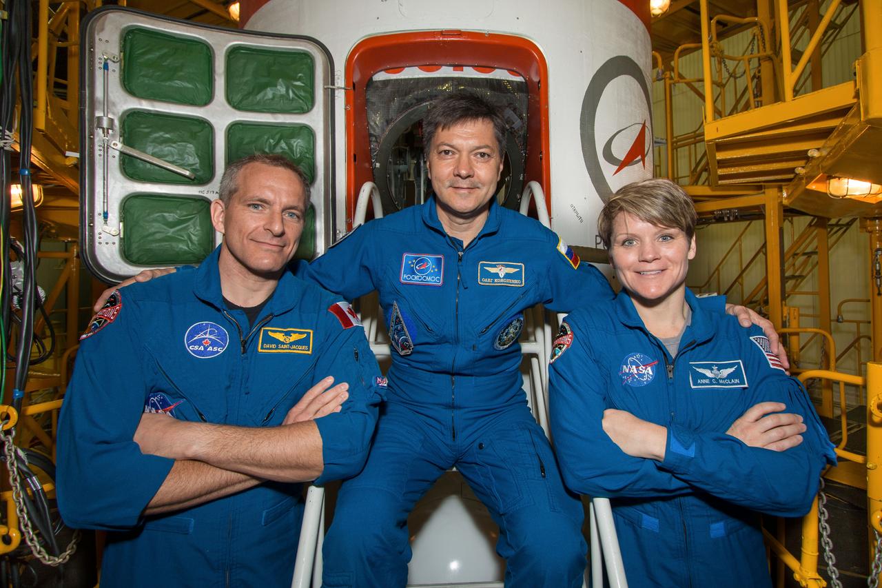jsc2018e051923 - In the Integration Facility at the Baikonur Cosmodrome in Kazakhstan, Expedition 56 backup crewmembers David Saint-Jacques of the Canadian Space Agency (left), Oleg Kononenko of Roscosmos (center) and Anne McClain of NASA (right) pose for pictures May 31 in front of the Soyuz MS-09 spacecraft as part of their final inspection of the vehicle. They are the backups to the prime crew, Serena Aunon-Chancellor of NASA, Sergey Prokopyev of Roscosmos and Alexander Gerst of the European Space Agency, who will launch June 6 in the Soyuz MS-09 spacecraft for a six-month mission on the International Space Station. ..NASA/Victor Zelentsov.