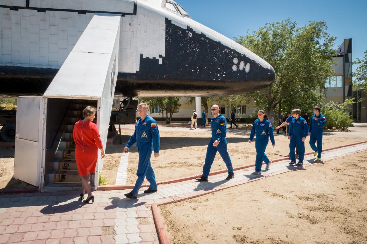 jsc2018e051936 - Outside the Korolev Museum at the Baikonur Cosmodrome in Kazakhstan, the Expedition 56 prime and backup crewmembers walk to a flight article of a Russian Buran space shuttle May 31 that is on display at the launch site as part of their pre-launch activities. Serena Aunon-Chancellor of NASA, Sergey Prokopyev of Roscosmos and Alexander Gerst of the European Space Agency will launch June 6 in the Soyuz MS-09 spacecraft for a six-month mission on the International Space Station. ..NASA/Victor Zelentsov.