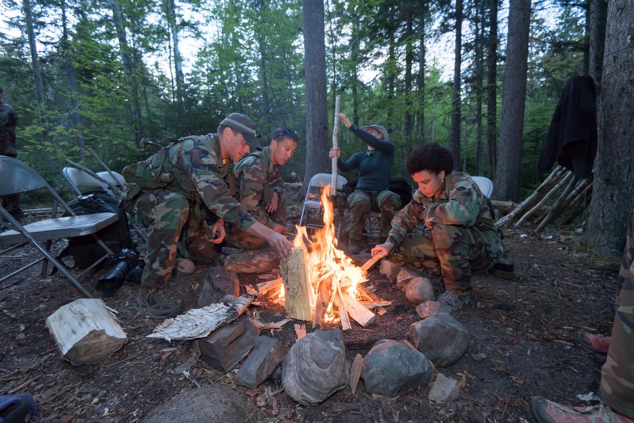 jsc2018e052190 (May 30, 2018) --- (From left) 2017 NASA astronaut candidates Bob Hines, Jonny Kim, and Jessica Watkins care for their fire while Canadian Space Agency astronaut candidate Jennifer Sidey-Gibbons preps more wood during wilderness survival training at the U.S. Navy’s Survival, Evasion, Resistance, and Escape School in Brunswick, Maine. Photo Credit: NASA/Josh Valcarcel