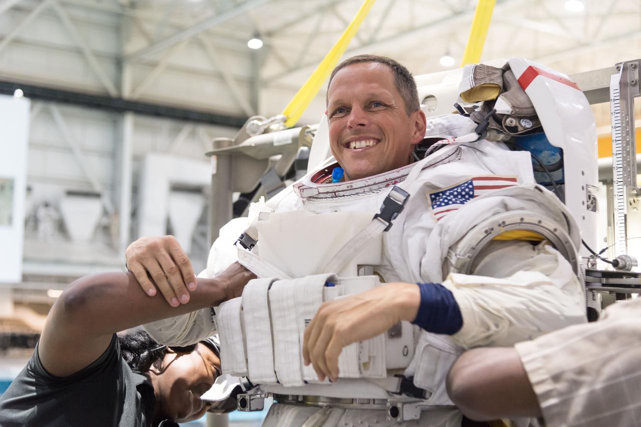 jsc2018e064795 (07/18/2018) --- 2017 NASA astronaut candidate Bob Hines is being helped into a spacesuit prior to underwater spacewalk training at NASA Johnson Space Center’s Neutral Buoyancy Laboratory in Houston. Photo Credit: (NASA/Norah Moran)