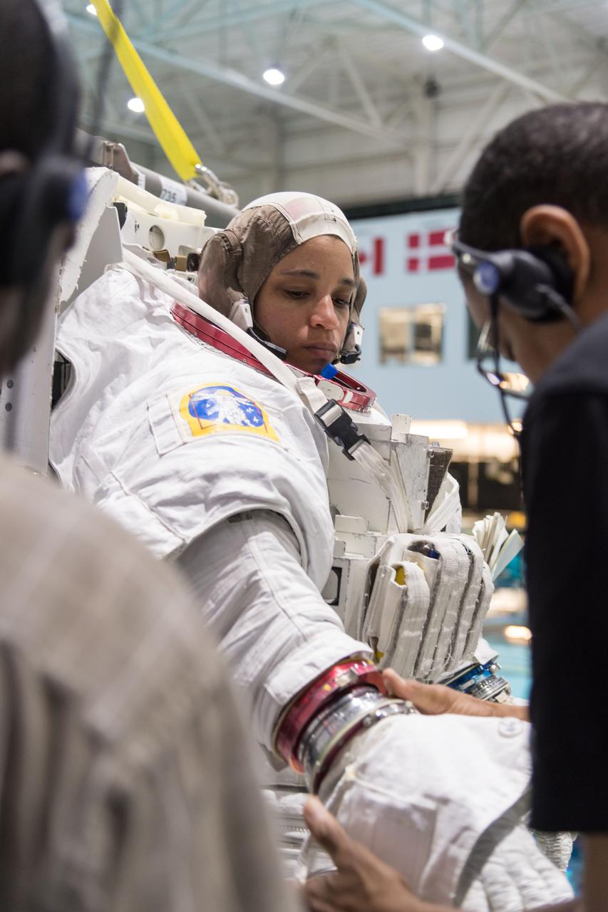 jsc2018e064818 (07/18/2018) --- 2017 NASA astronaut candidate Jessica Watkins being helped into a spacesuit prior to underwater spacewalk training at NASA Johnson Space Center’s Neutral Buoyancy Laboratory in Houston. Photo Credit: (NASA/Norah Moran)