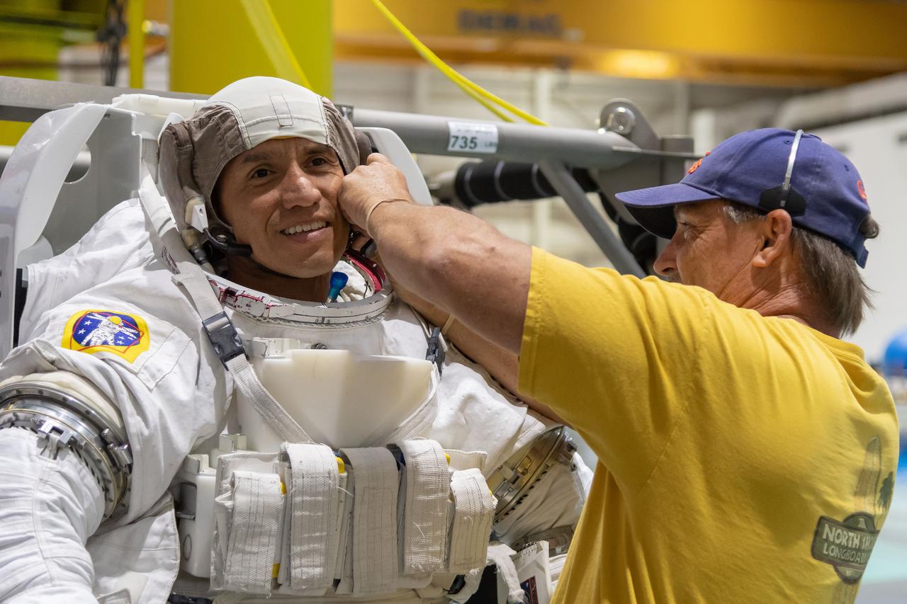 jsc2018e065029 (July 19, 2018) --- 2017 NASA astronaut candidate Frank Rubio is being helped into a spacesuit prior to underwater spacewalk training at NASA Johnson Space Center’s Neutral Buoyancy Laboratory in Houston. Photo Credit: (NASA/Josh Valcarcel)