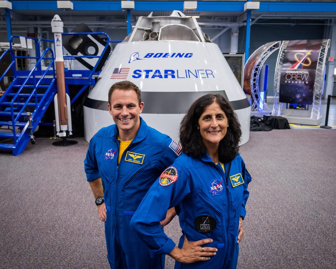 jsc2018e067953 (Aug. 2, 2018) --- NASA astronauts Josh Cassada (left) and Suni Williams pose for a portrait in front of the Boeing CST-100 Starliner Commercial Crew vehicle mock up at NASA's Johnson Space Center in Houston, Texas.