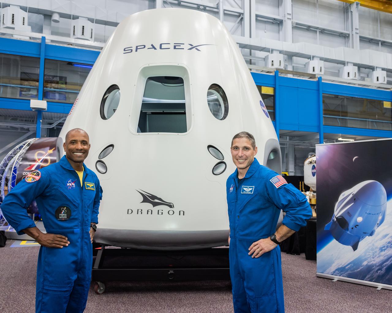 jsc2018e067958 (Aug. 2, 2018) --- NASA astronauts Victor Glover (left) and Mike Hopkins pose for a portrait in front of the SpaceX Dragon Commercial Crew spacecraft mock up at NASA's Johnson Space Center in Houston, Texas.