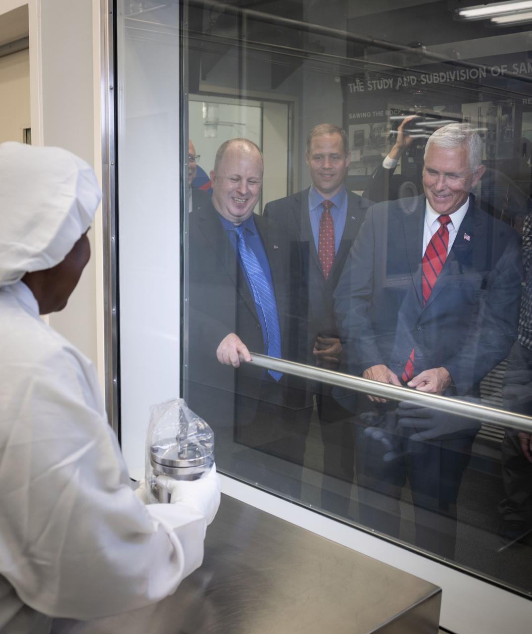 jsc2018e076655 (Aug. 23, 2018) --- Vice President Mike Pence visited NASA’s Johnson Space Center in Houston on Aug. 23, 2018, to discuss the future of space exploration and other elements of human spaceflight. During his trip to the Johnson Space Center, the Vice President also toured the laboratory housing the moon rocks retrieved during the Apollo program’s lunar missions and extraterrestrial samples from other uncrewed sample return missions. Apollo Lunar Sample Principle Scientist Andrea Mosie held a lunar sample up for inspection by the Vice President, who was joined in the viewing room behind protective glass by Apollo Lunar Sample Curator Ryan Ziegler.
