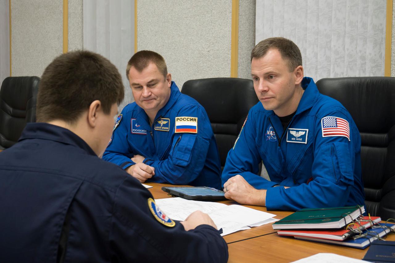 jsc2018e085897 (Oct. 3, 2018) --- Expedition 57 crew members Alexey Ovchinin of Roscosmos, left, and Nick Hague of NASA, right, review training documents with a Gagarin Cosmonaut Training Center instructor as they prepare for their upcoming launch, Wednesday, Oct. 3, 2018 at the Cosmonaut Hotel in Baikonur, Kazakhstan. Ovchinin and Hague are scheduled to launch on Oct. 11 onboard the Soyuz MS-10 spacecraft from the Baikonur Cosmodrome in Kazakhstan for a six-month mission on the International Space Station. Photo Credit: (NASA/Victor Zelentsov)
