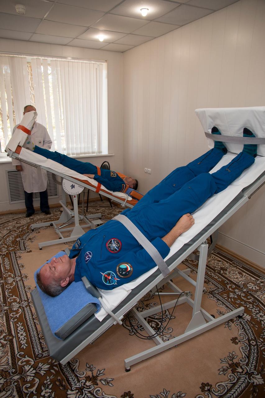 jsc2018e085901 (Oct. 3, 2018) --- Expedition 57 backup crew members Oleg Kononenko of Roscosmos, top, and David Saint-Jacques of the Canadian Space Agency, bottom, conduct tests of their vestibular system on tilt tables, Wednesday, Oct. 3, 2018 at the Cosmonaut Hotel in Baikonur, Kazakhstan. Alexey Ovchinin of Roscosmos and Nick Hague of NASA are scheduled to launch on Oct. 11 onboard the Soyuz MS-10 spacecraft from the Baikonur Cosmodrome in Kazakhstan for a six-month mission on the International Space Station. Photo Credit: (NASA/Victor Zelentsov)
