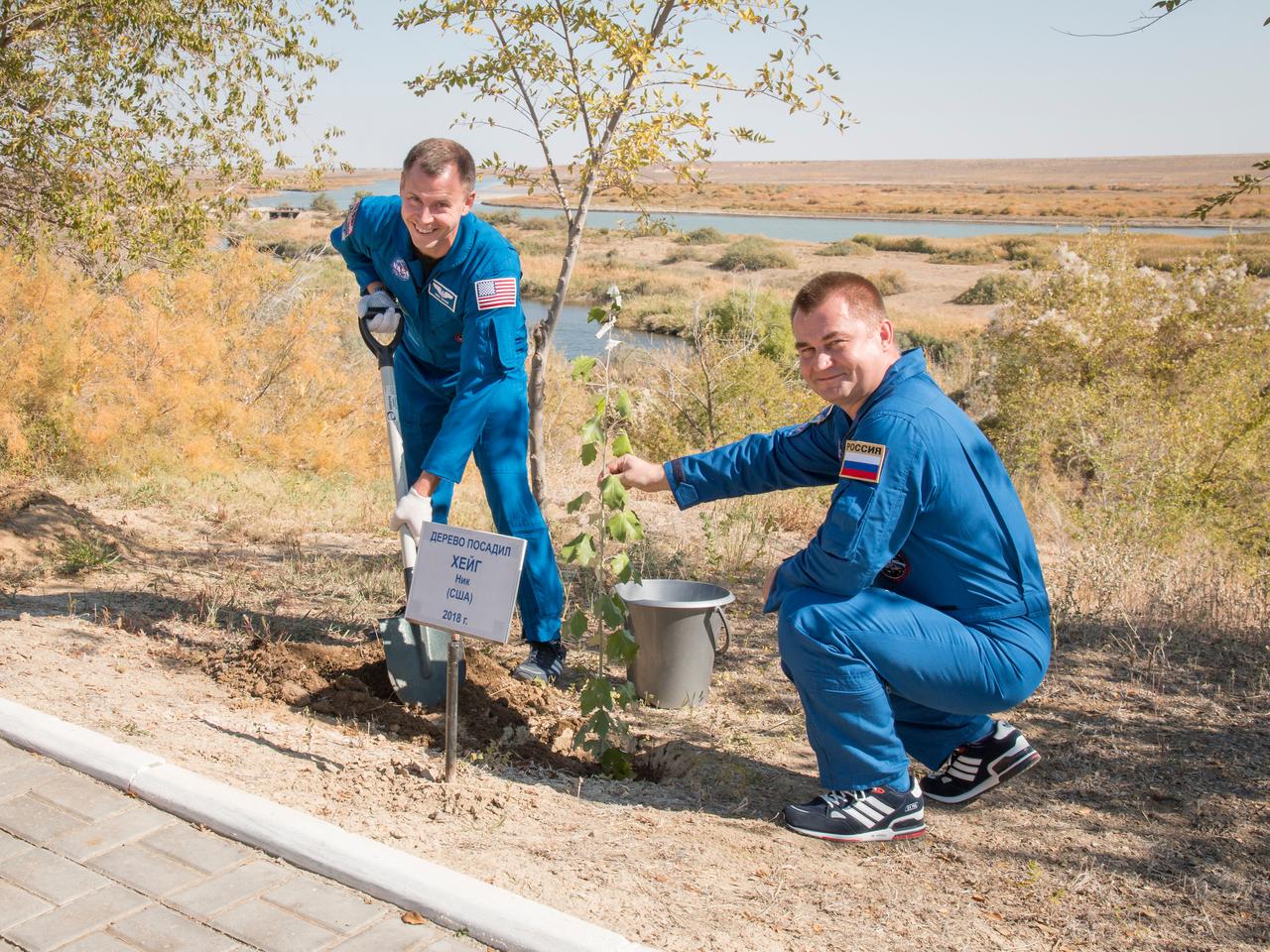 jsc2018e085903 (Oct. 3, 2018) --- Expedition 57 crew member Nick Hague of NASA, left, plants a tree in his name as part of the traditional pre-launch activities for a first-time flier with help from crewmate Alexey Ovchinin of Roscosmos, Wednesday, Oct. 3, 2018 at the Cosmonaut Hotel in Baikonur, Kazakhstan. Hague and Ovchinin are scheduled to launch on Oct. 11 onboard the Soyuz MS-10 spacecraft from the Baikonur Cosmodrome in Kazakhstan for a six-month mission on the International Space Station. Photo Credit: (NASA/Victor Zelentsov)