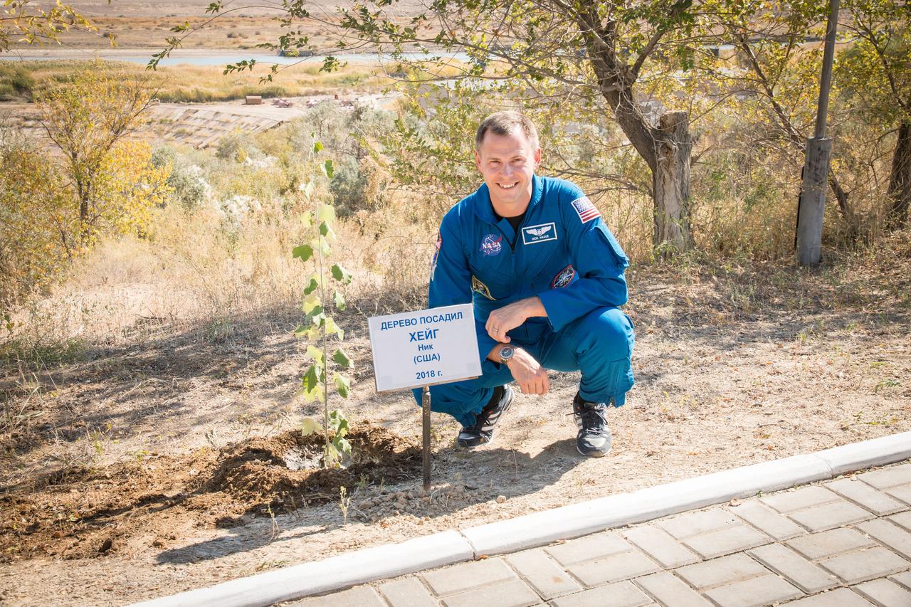 jsc2018e085905 (Oct. 3, 2018) --- Expedition 57 crew member Nick Hague of NASA poses for a picture with the tree that he planted in his name as part of the traditional pre-flight activities for first-time fliers, Wednesday, Oct. 3, 2018 at the Cosmonaut Hotel in Baikonur, Kazakhstan. Hague and Alexey Ovchinin of Roscosmos are scheduled to launch on Oct. 11 onboard the Soyuz MS-10 spacecraft from the Baikonur Cosmodrome in Kazakhstan for a six-month mission on the International Space Station. Photo Credit: (NASA/Victor Zelentsov)