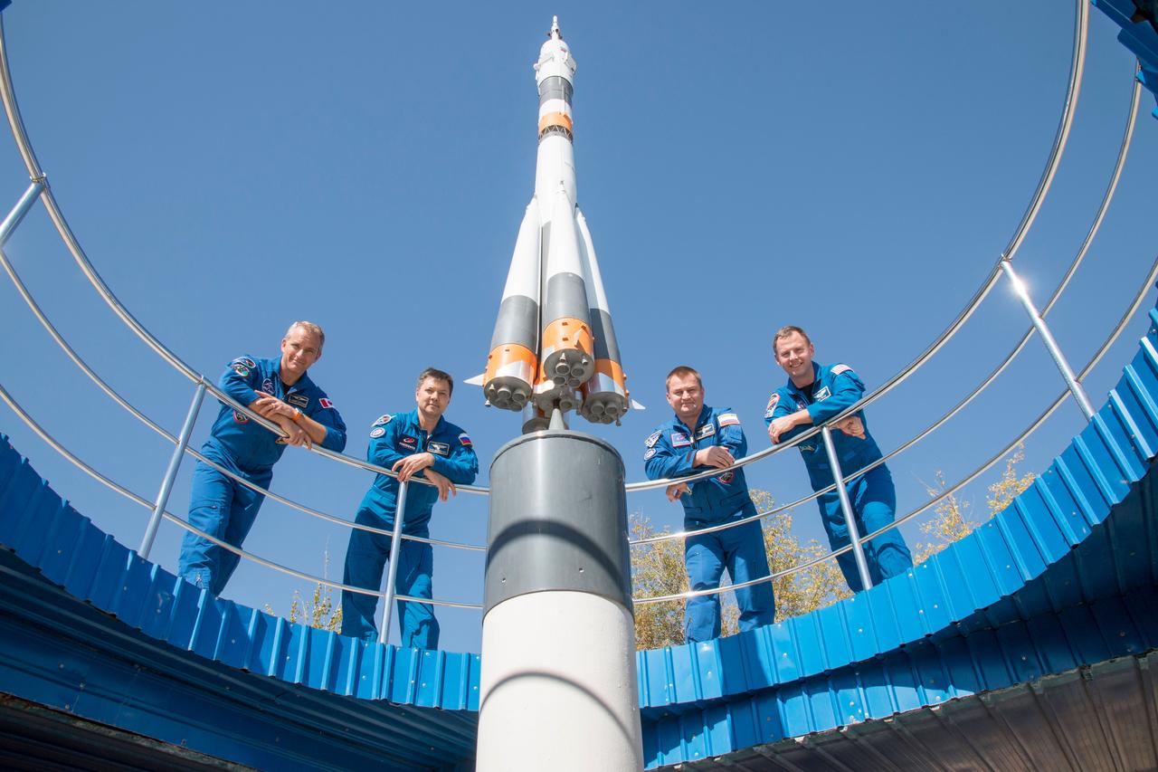 jsc2018e085906 (Oct. 3, 2018) --- Expedition 57 backup and prime crew members pose for pictures flanking a model of a Soyuz rocket, Wednesday, Oct. 3, 2018 at the Cosmonaut Hotel crew quarters in Baikonur, Kazakhstan. From left are backup crew members David Saint-Jacques of the Canadian Space Agency and Oleg Kononenko of Roscosmos and prime crew members Alexey Ovchinin of Roscosmos and Nick Hague of NASA. Ovchinin and Hague are scheduled to launch on Oct. 11 onboard the Soyuz MS-10 spacecraft from the Baikonur Cosmodrome in Kazakhstan for a six-month mission on the International Space Station. Photo Credit: (NASA/Victor Zelentsov)