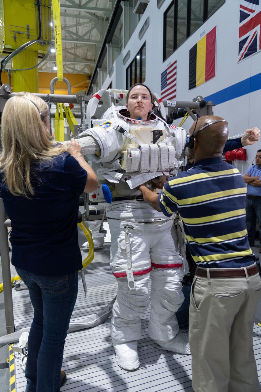 jsc2018e095898 (November 7, 2018) --- 2017 NASA astronaut candidate Kayla Barron is helped into a spacesuit prior to underwater spacewalk training at NASA Johnson Space Center’s Neutral Buoyancy Laboratory in Houston. Photo Credit: (NASA/Robert Markowitz)
