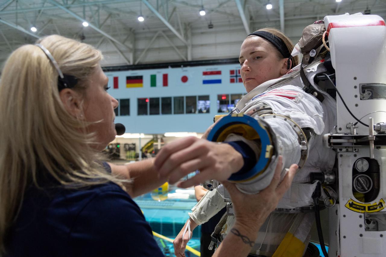 jsc2018e095900 (November 7, 2018) --- 2017 NASA astronaut candidate Kayla Barron is helped into a spacesuit prior to underwater spacewalk training at NASA Johnson Space Center’s Neutral Buoyancy Laboratory in Houston. Photo Credit: (NASA/Robert Markowitz)