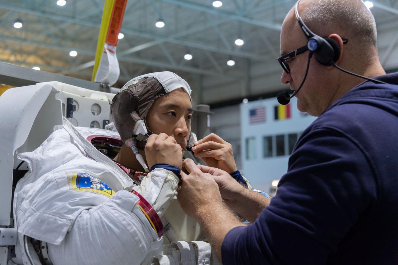jsc2018e095911 (November 7, 2018) --- 2017 NASA astronaut candidate Jonny Kim is helped into a spacesuit prior to underwater spacewalk training at NASA Johnson Space Center’s Neutral Buoyancy Laboratory in Houston. Photo Credit: (NASA/Robert Markowitz)
