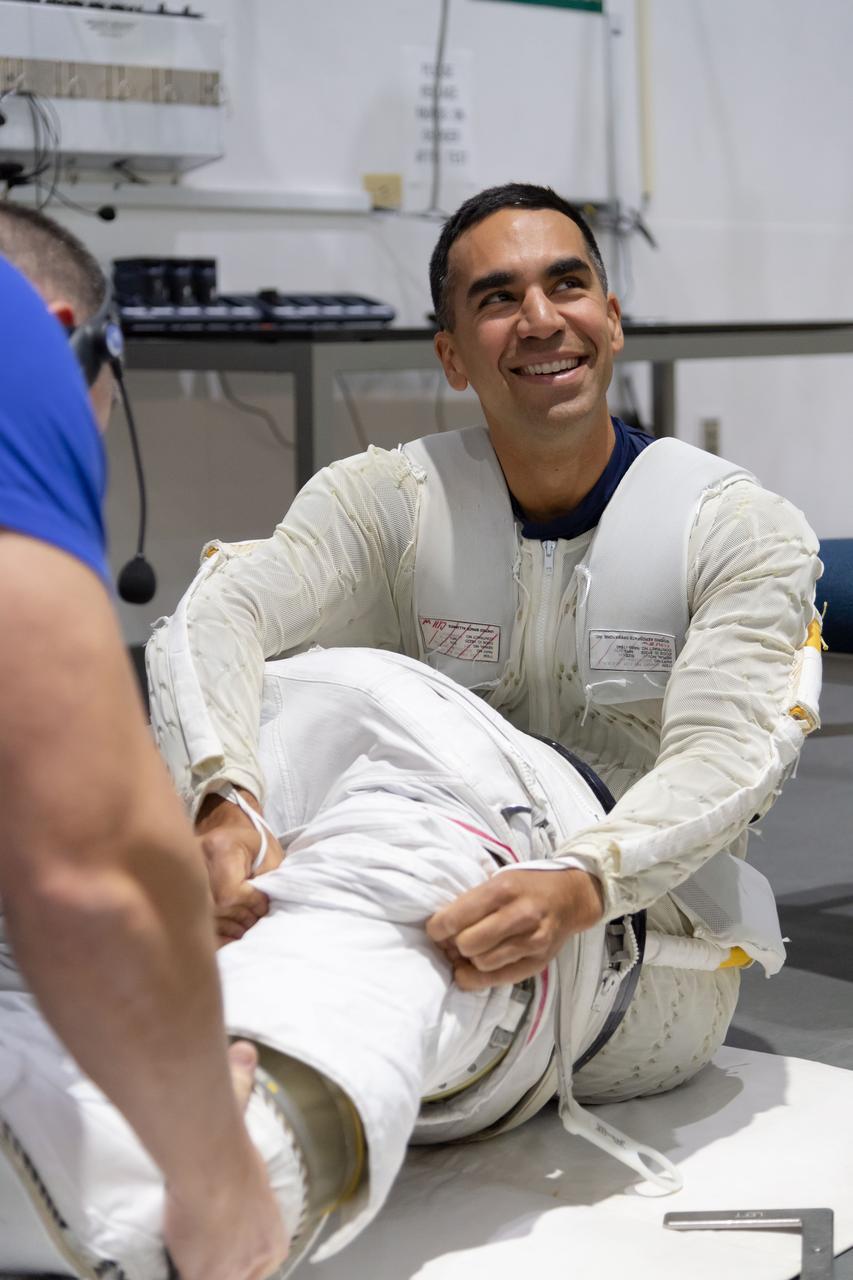 jsc2018e096661 (November 7, 2018) --- 2017 NASA astronaut candidate Raja Chari wears a Liquid Cooling and Ventilation Garment and is helped into a spacesuit prior to underwater spacewalk training at NASA Johnson Space Center’s Neutral Buoyancy Laboratory in Houston. The cooling garment distributes water throughout to help keep him cool while training underwater in the spacesuit. Photo Credit: (NASA/Robert Markowitz)