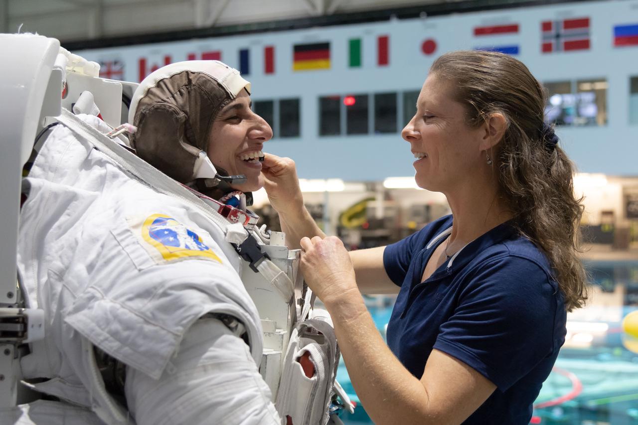 jsc2018e096672 (November 7, 2018) --- 2017 NASA astronaut candidate Jasmin Moghbeli is helped into a spacesuit by NASA astronaut Tracy Caldwell Dyson prior to underwater spacewalk training at NASA Johnson Space Center’s Neutral Buoyancy Laboratory in Houston. Photo Credit: (NASA/Robert Markowitz)