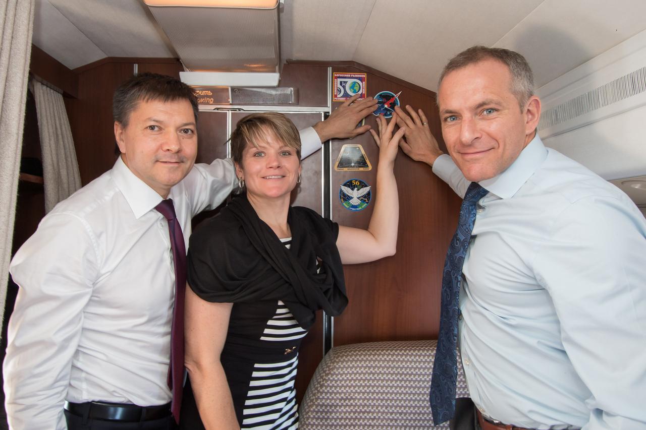 jsc2018e097261 - Aboard a Gagarin Cosmonaut Training Center aircraft, Expedition 58 crewmembers Oleg Kononenko of Roscosmos (left), Anne McClain of NASA (center) and David Saint-Jacques of the Canadian Space Agency (right) affix a Soyuz MS-11 sticker to the wall of the cabin Nov. 19 in a traditional ceremony as they flew to their launch site in Baikonur, Kazakhstan. They will launch Dec. 3 on the Soyuz MS-11 spacecraft from the Baikonur Cosmodrome in Kazakhstan for a six-and-a-half month mission on the International Space Station...NASA/Victor Zelentsov.